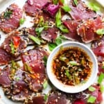 Slices of ahi tuna tataki with sesame seeds and scallions, served with dipping sauce.