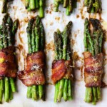Crispy bacon-wrapped asparagus bundles garnished with grated cheese and lemon zest.