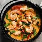A bowl of shrimp coconut curry with herbs and spices.