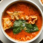 Bowl of lasagna soup with pasta, basil, and pepper garnish.