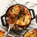 A bowl of French onion soup with melted cheese and thyme garnish.