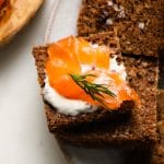 Rye bread topped with gravlax, mustard sauce, and a dill sprig.