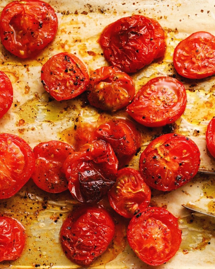 Roasted tomatoes with olive oil and pepper on a baking sheet.