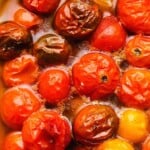 Juicy red tomatoes cooked in oil, showing rich and glossy textures.