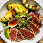 A bowl of seared ahi tuna with grilled avocado and green onions.