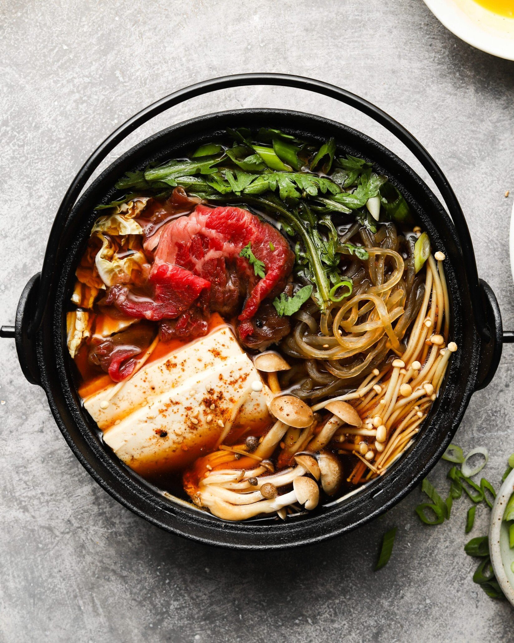A pot of Japanese Sukiyaki with beef, tofu, mushrooms, and vegetables.