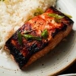 Miso salmon with sesame seeds and green onions served alongside white rice.