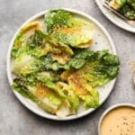 Little Gem lettuce salad with grated cheese and breadcrumbs on a white plate.
