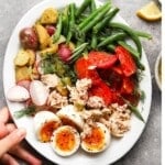 Colorful Tuna Nicoise Salad with eggs, tomatoes, green beans, potatoes, and radishes.