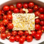 Cherry tomatoes and seasoned feta cheese in a white baking dish.