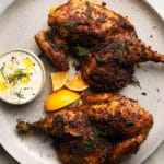 Roasted chicken with harissa and sumac, served with tzatziki and lemon wedges.