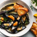 Steamed mussels in white wine sauce with herbs and toasted bread.