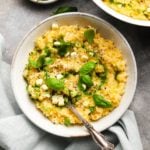 Creamy corn risotto garnished with basil leaves and drizzled with green oil.