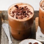A glass of mocha iced coffee topped with chocolate shavings on a tray.