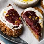 Sesame toast with whipped ricotta, strawberry jam, and lemon zest garnish.