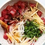 Ahi tuna poke bowl with onions, sesame seeds, scallions, and ginger in a bowl.