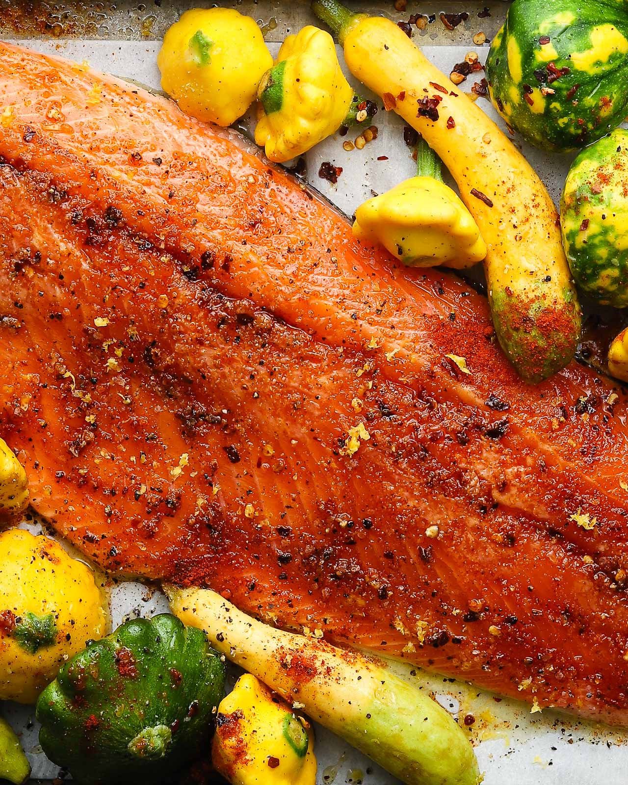 A sheet tray of steelhead trout before being roasted with zucchini.