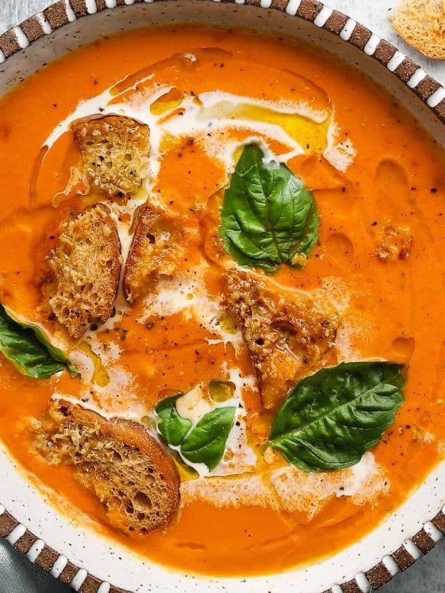 Creamy roasted tomato soup with Gruyere toasts and fresh basil leaves.