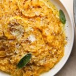 Creamy honeynut squash risotto with shaved cheese and fresh sage leaves.