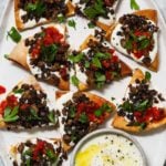 Pita slices topped with spiced lamb, whipped feta, parsley, and red sauce.