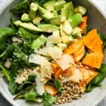 Fresh salad with avocado, persimmon, quinoa, spinach, pine nuts, and parmesan cheese.