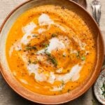 Creamy butternut squash soup garnished with fresh thyme and black pepper.