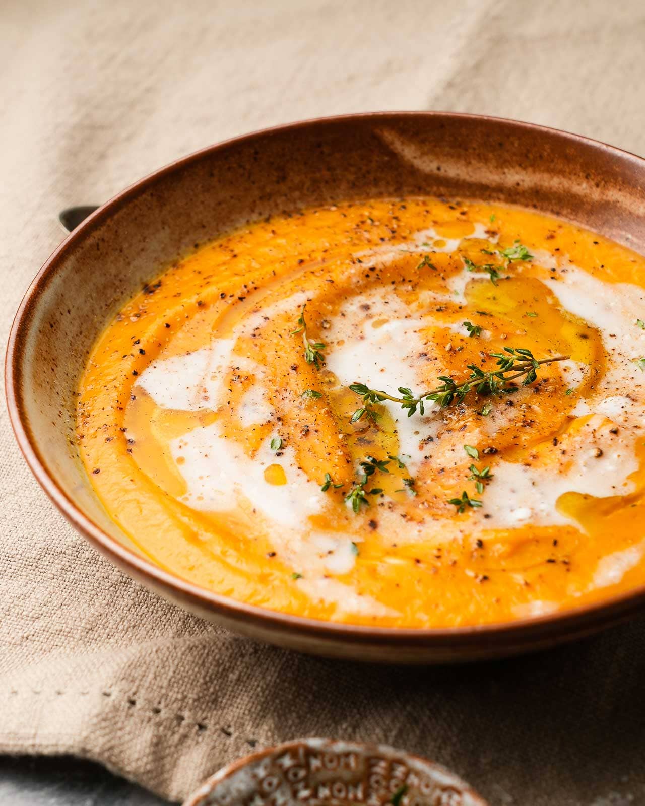 Creamy butternut squash soup with herbs and cracked pepper garnish.