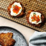 Crispy potato latkes topped with cream and roe on a cooling rack.
