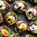 Seared ahi tuna cucumber bites topped with wasabi mayo and edible flowers.