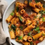 Pasta with cauliflower mushroom bolognese, garnished with fresh parsley and grated cheese.