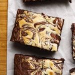 Brownie slice with a marbled cheesecake swirl pattern on parchment paper.