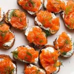 Crostini topped with gravlax, dill yogurt, and fresh dill sprigs, arranged on a platter.