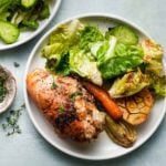 Roasted chicken breast with lettuce, cucumber, carrot, fennel, and garlic on a plate.