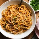 A bowl of caramelized cabbage and leek pasta topped with chopped herbs.