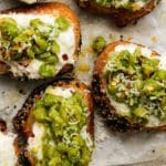 Toasted bread topped with smashed peas and cheese on a tray.