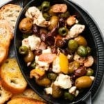 Mixed olives and feta with citrus and herbs, served with toasted bread slices.