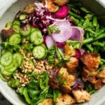 A colorful salad with cucumbers, radishes, asparagus, za'atar croutons, and pine nuts.