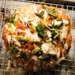 Whole roasted cauliflower with miso tahini sauce and green onion garnish.