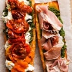 Open-faced sandwich with roasted tomatoes, ricotta, pesto, and prosciutto on crusty bread.