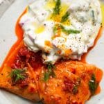 Spicy roasted salmon topped with creamy yogurt sauce and fresh dill garnishes.