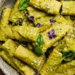 Rigatoni with green sauce, topped with fresh basil and purple flowers.