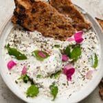 Creamy yogurt dip with herbs, edible flowers, and crispy sesame flatbread.