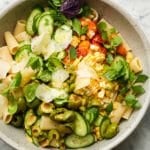 A vibrant pasta salad with cucumbers, tomatoes, corn, olives, and Parmesan.