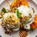 Grilled peaches with ice cream, topped with crushed nuts and mint leaves.