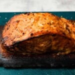 Grilled salmon on a charred cedar plank with spices and seasoning.
