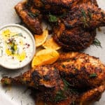 Spiced roast chicken with herbs, served with yogurt sauce and lemon wedges.