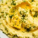 Creamy mashed potatoes with melted butter, chopped chives, and pepper seasoning.