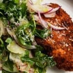 Crispy chicken with fennel, arugula salad topped with red onion and grated cheese.