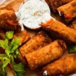 Crispy buffalo chicken egg rolls with dip and celery garnishes.