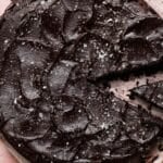 Dense chocolate cake topped with coarse salt, one slice partially removed.
